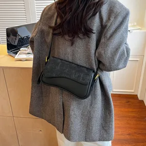Stylish black shoulder bag for women, chic curved flap design, and elegant embossed texture.