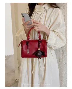 Détail de sac Boston en cuir PU rouge avec charme rétro élégant et poignée chic et mode.