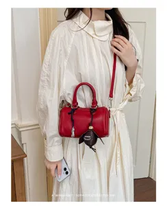 Mini sac bandoulière cylindrique en cuir PU rouge avec poignées et charmant pendentif.