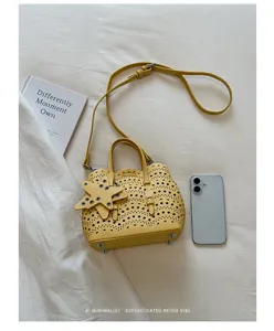 Borsa a tracolla gialla traforata con ciondolo a stella e manico per stile quotidiano.