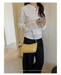 Yellow quilted baguette underarm shoulder bag with stylish chain strap and cute cherry charm.