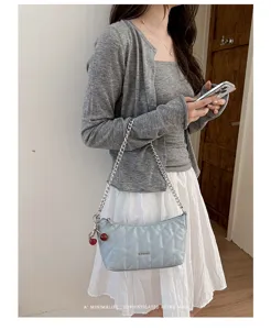 Detail view of the stylish light blue quilted shoulder bag with chain strap and cute cherry charm.