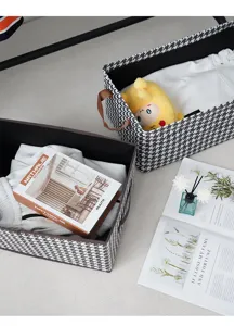 Υφασμάτινο κουτί αποθήκευσης με μοτίβο pied-de-poule και καφέ χερούλια για ρούχα.