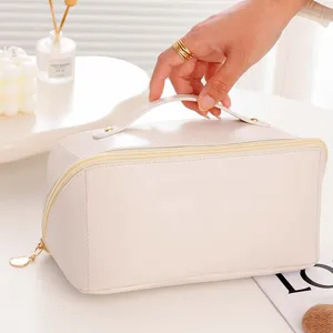 Beige PU leather cosmetic bag with handle, large capacity portable travel makeup organizer.