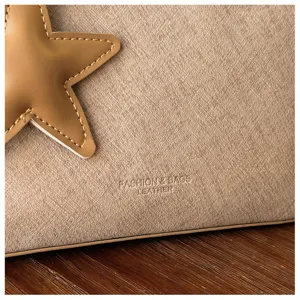 Nahaufnahme einer stilvollen khakifarbenen Ledertasche mit Stern-Applikation und feiner Textur.