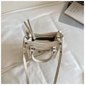Petit sac bandouliere moto blanc avec rivets metalliques et fermeture eclair elegante.