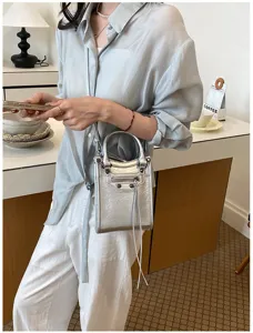 Vue détaillée du sac bandoulière moto argenté métallisé avec clous et zips à franges.