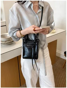 Mini sac bandoulière de moto en cuir noir avec clous, fermetures éclair et pompons.