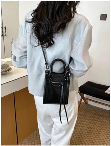Vue détaillée du sac bandoulière noir de style moto avec rivets, franges et poignées.