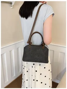 Detailansicht der stylischen dunkelgrauen Umhängetasche mit braunem Griff am Model.