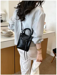 Vue détaillée du sac bandoulière moto en cuir noir avec clous métalliques et poche zippée.