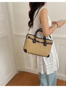 Woven straw shoulder bag with brown leather trim, casual summer commuting handbag detail shot.