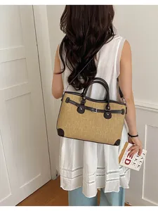 Detailed view of a chic summer straw shoulder handbag with contrast dark brown leather trim.