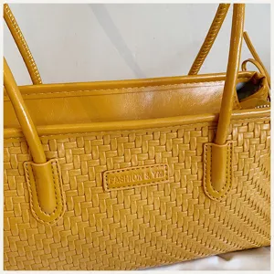 Primer plano del bolso de hombro amarillo tejido de piel sintética texturizada con asas dobles.