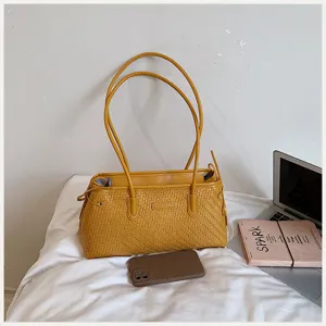 Vista detallada del elegante bolso de hombro tejido amarillo con asas dobles para mujeres.