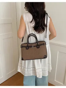 Detail view of the stylish brown canvas shoulder bag, featuring leather trim and buckle accent.