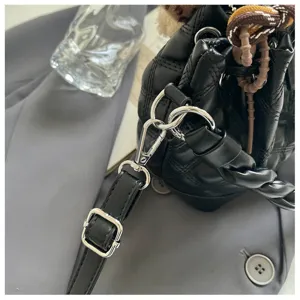 Detailed view of women black quilted bucket shoulder bag featuring silver hardware and braided strap.