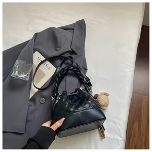 Black quilted bucket bag detail shot showcasing textured pattern and braided handle design.