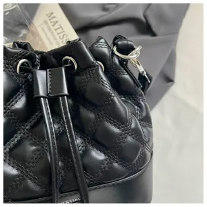 Black quilted bucket bag detail shot, stylish shoulder bag with drawstring closure for women.