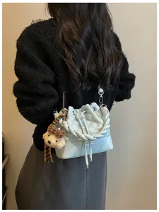 Light blue quilted bucket bag detail view with braided handle, drawstring and cute bear charm.
