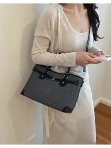 Detailed view of the stylish grey fabric shoulder bag with chic black leather straps and buckles.