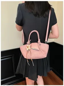 Detailansicht der stilvollen rosa Umhängetasche mit Blumenanhänger im modischen Alltagslook.