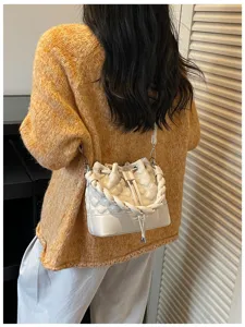 Detailed view of women's white quilted bucket bag with braided strap and chic commuting style.