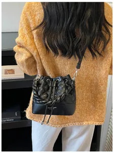 Detailed view of women's black quilted bucket bag with braided handle and chic drawstring.