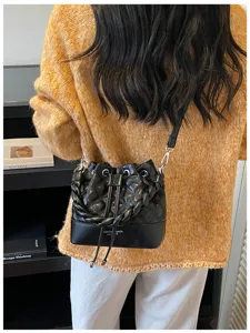 Detailed view of a black quilted bucket bag with braided handle and drawstring closure.
