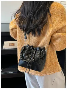 Black quilted bucket shoulder bag with braided handle and drawstring detail for daily commute.