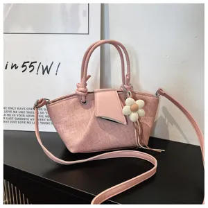 Einfache rosafarbene Umhängetasche aus Canvas mit Henkeln und süßem Strickblumen-Anhänger.