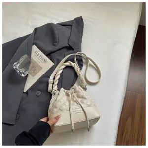 Detailed view of fashionable quilted bucket shoulder bag with braided handle and drawstring.