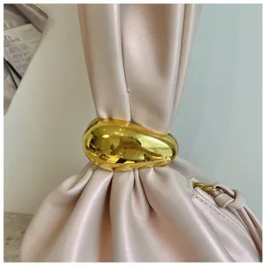 Nahaufnahme einer modischen plissierten rosa Lederhandtasche mit glänzendem goldenem Metallring.