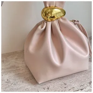 Detailansicht einer trendigen, minimalistischen pinken Plissee-Beuteltasche mit goldenem Ring.