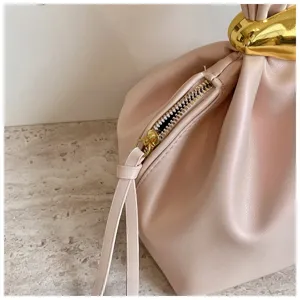 Nahaufnahme der stilvollen minimalistischen Faltenhandtasche mit goldenem Metallgriff.