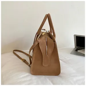 Detailed side view of vintage suede Boston handbag with shoulder strap and gold hardware.