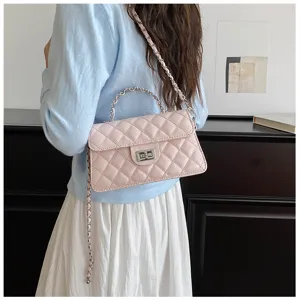 Detailed view of fashionable pink quilted chain shoulder bag worn by model in elegant indoor setting.