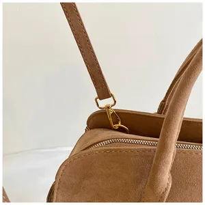 Close-up detail of women brown suede boston bag showing zipper and metal hardware.