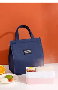 Detail view of a blue insulated lunch bag featuring top handles and secure zipper closure.
