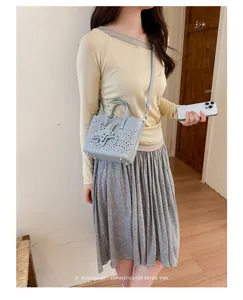 Vista dettagliata della borsa a tracolla azzurra traforata con decorazione a stella unica.