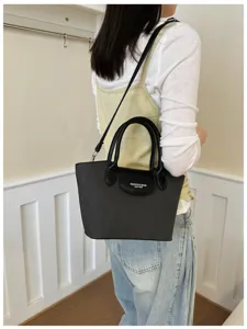 Black leather shoulder dumpling bag detail, minimalist design with top handle and crossbody strap.