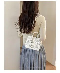 Elegante borsa a tracolla bianca con motivo traforato e ciondolo a stella in primo piano.