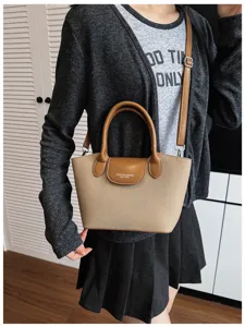 Detail view of canvas and leather crossbody dumpling handbag worn by model, simple chic style.