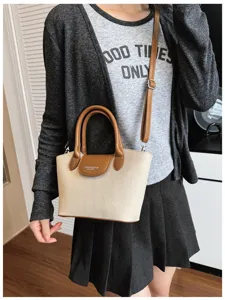 Canvas shoulder bag detail showing brown leather flap and comfortable handle construction.