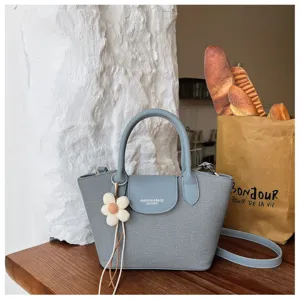 Detailed shot of a chic blue dumpling tote bag with a cute flower charm and stylish handle.