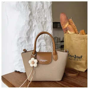 Canvas leather contrast handbag detail, stylish dumpling tote bag with cute flower pendant charm.