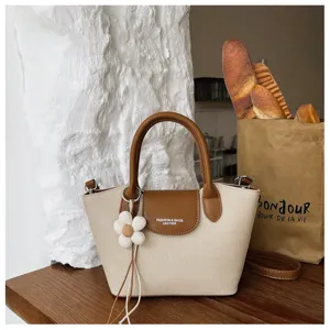 Canvas dumpling handbag with cute daisy pendant, top handle and adjustable shoulder strap detail.