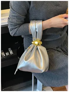 Einfallsreiche silberne Metallic Handtasche mit auffälligem goldenem Knotendetail.