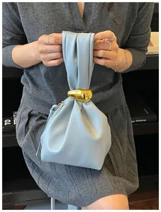 Minimalistische geraffte Handgelenktasche aus hellblauem Leder mit goldenem Metalldetail.