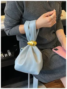 Detailansicht der hellblauen Falten-Handtasche mit elegantem goldenen Metallknoten-Akzent.